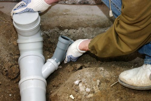 bigstock-Plumber-assembling-pvc-sewage-48326390
